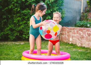 Two Children With Beach Ball At Swimming Pool. Joyful Kid Playing In Inflatable Pool In Backyard. Little Kids At Swimming Pool On Sunny Day. Colorful Swimming Pool Ball. Healthy Babies Summer Activity