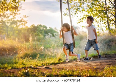 Two children, boy brothers, having fun on a swing in the backyard on sunset - Powered by Shutterstock