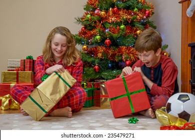 Two Children, A Boy And A Girl, Opening Their Presents On Christmas Morning.