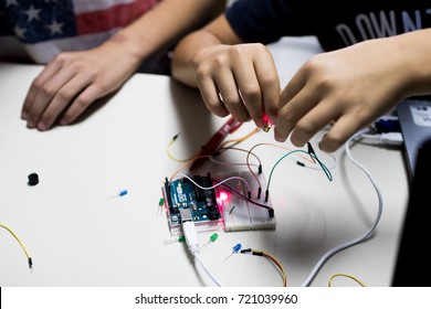zwei Kinder bauen einen Prototypkreis mit einem roten Laser, der von einem Mikrocontroller gesteuert wird. SCHRITT- und Programmieraktivitäten