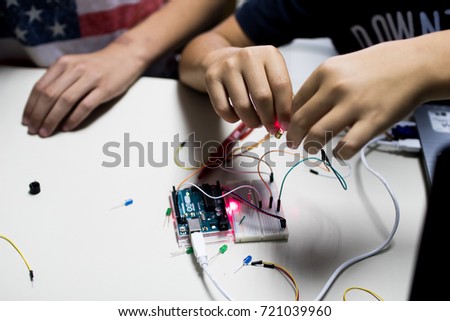two children build a prototype circuit with a red laser controlled by a microcontroller. STEAM and coding activity