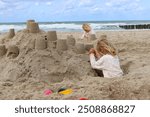 
Two children build a sandcastle on the beach.