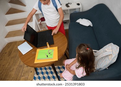 Two children collaborating on a homework assignment using a laptop at a cozy home setting. - Powered by Shutterstock