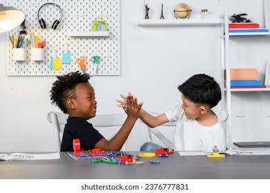 Two Children of different ethnicities high-fived each other after completing a collaborative project on electrical circuits. Children were proud of their accomplishments and Brainstormed ideas. - Powered by Shutterstock