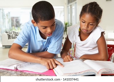 Two Children Doing Homework Together In Kitchen