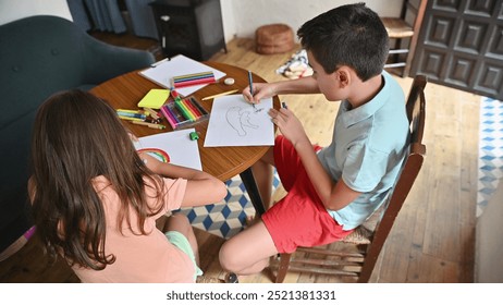 Two children engaged in a fun drawing activity at home with colorful supplies, encouraging creativity and learning.