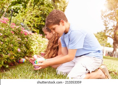 Two Children Having Easter Egg Hunt In Garden