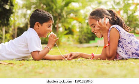 Two Children Having Fun By Playing With String Telephone At Park During Vacation - Concept Of Brain Development And Socializing By Playing Outdoor Games In The Technology Driven World.