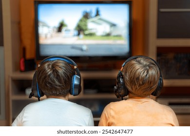 Two children with headphones on their backs, in front of a television in their living room. Concept of video game - Powered by Shutterstock