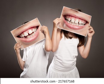 dos niños sosteniendo una foto de una boca sonriendo