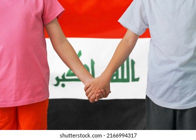 Two Children Joined Hands On Flag Iraq Background. Boy And Girl Joined Hands On Background Flag Of Iraq. Concept Of Family And Parenting In Iraq