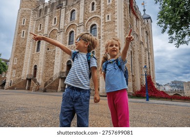 Two children joyfully point while exploring the historic Tower of London, showcasing their curiosity and excitement in England, UK