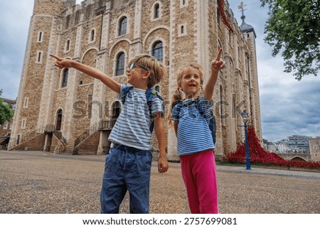 Two children joyfully point while exploring the historic Tower of London, showcasing their curiosity and excitement in England, UK