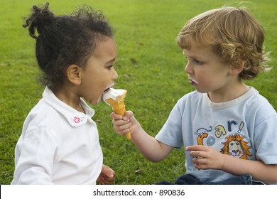 Two children, one a blond boy, one a mixed race girl sharing an ice cream