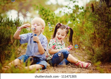 Two Children In The Park Blowing Soap Bubbles And Having Fun