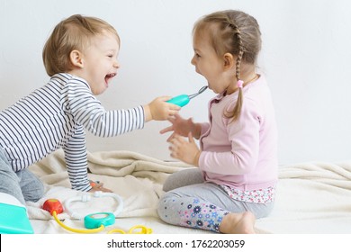 Two children play doctor in the nursery. Brother in yellow glasses treats his sister, playing dentist, ENT, ophthalmologist, temperature measurement. Role-playing games for children