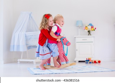 Two children play indoors. Kids riding toy rocking horse. Boy and girl playing at day care or kindergarten. Beautiful nursery for baby and toddler. Toys for preschool child. Brother and sister at home