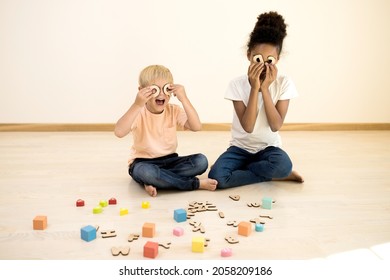 Two Children Play On A Wooden Floor With Educational Toys. Girl And Little Boy Have Fun Playing With Letters Of English Alphabet. Language Learning, Home Schooling, Family Concept. Lifestyle. At Home.