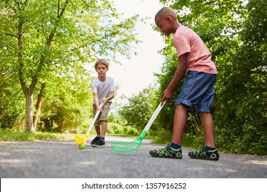 Two children play street hockey together as sport in summer vacation