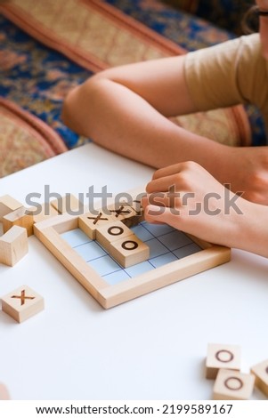 Two children are playing Bingo board Tic-tac-toe game. Cozy home. Joy and fun. Play time. Indoor activity. Classes for children of preschool and primary school age. The development of mindfulness.