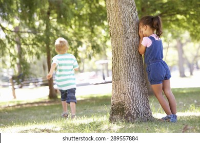 Two Children Playing Hide And Seek In Park