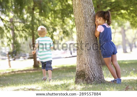 Two Children Playing Hide And Seek In Park