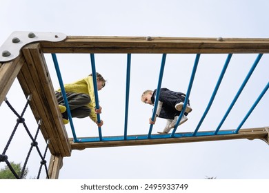 Two children playing in a playground climbing a structure - Powered by Shutterstock