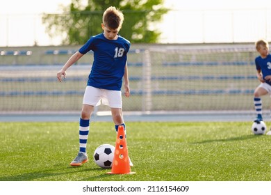 Two Children Playing Soccer On Training Session. Happy Boys Practicing Football During Summer Camp. Kids In Football Club Wearing Blue Jersey Shirts And Soccer Kits