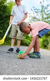 Two children playing street hockey with ball in the park