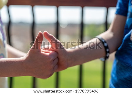Two children playing a thumb war battle with the objective to pin the opposing player's thumb