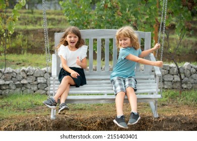 Two children swinging outdoors. Portrait of adorable brother and sister smile and laugh together while sitting on swing outdoors. Happy lifestyle kids.