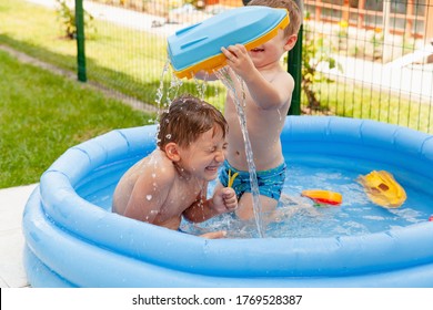 Two Children With Toys At Swimming Pool. Joyful Kid Playing In Inflatable Pool On The Backyard. Little Kids At Swimming Pool On Sunny Day. Healthy Kids Summer Activity.