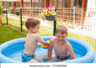 Two Children With Toys At Swimming Pool. Joyful Kid Playing In Inflatable Pool On The Backyard. Little Kids At Swimming Pool On Sunny Day. Healthy Kids Summer Activity.