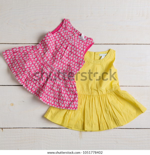 two children's dresses on a wooden board, concept of summer, white boards