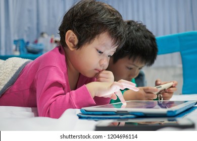 Two Chinese Children Addicted Tablet, Asian Child Watching Tablet, Kid Use Telephone Together On Their Bed, Play Phone, Kid Addict Smartphone
