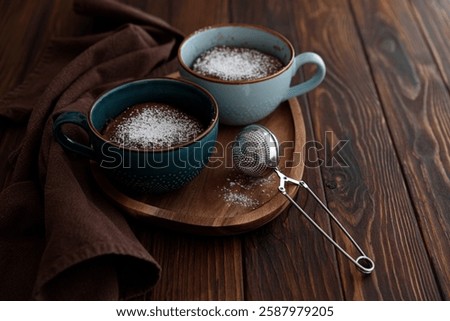 Two chocolate mug cake under sugar icing on dark wooden table. Easy homemade dessert. Mugcake from microwave