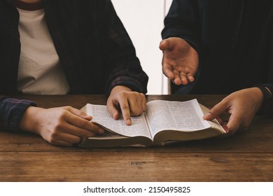 Two christianity sitting around wooden table with open holy bible study reading together in Sunday school. Christian bible god deliver devotional with hand friendship. - Shutterstock ID 2150495825