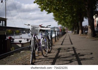 Two city woman bikes parked on pathway on riverside at bristol, UK. Bright lady bicycles vintage style with baskets in summer sunny town. Elegant recreational vehicles - Powered by Shutterstock