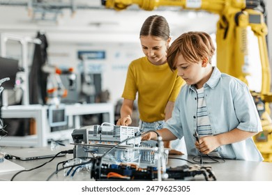 Two classmates working togeter on circuit board, building robot in after-school robotics club. Children learning robotics in Elementary school. - Powered by Shutterstock