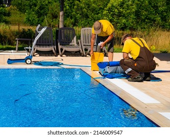 Two Cleaners Wash A Pool Cleaning Robot.Concept Photo  Pool Cleaning, Hotel Staff, Service.