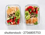Two clear meal prep containers hold servings of chicken, quinoa, tomatoes, cucumbers, and guacamole with lime. This is good for a balanced lunch or dinner.