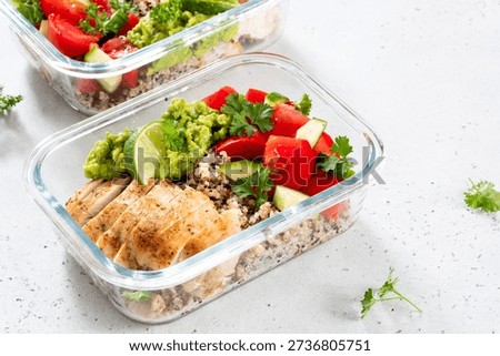 Two clear meal prep containers hold servings of chicken, quinoa, tomatoes, cucumbers, and guacamole with lime. This is good for a balanced lunch or dinner.
