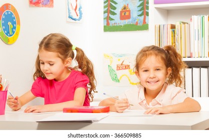 Two clever schoolgirls writing at the copybook - Shutterstock ID 366509885