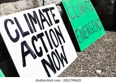 Two 'Climate action now' and 'climate emergency' signs rest on a sidewalk during a climate change march in London, Ontario, Canada in September, 2021. No people.