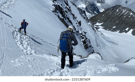 Two climbers are standing at the top of the Delaunay Pass. Climbing Belukha. Altai Mountains. View of mountain ranges, hills and peaks. Beautiful snowy winter landscape.