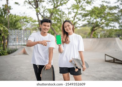 Two close friends share a fun moment at a lively skate park, holding skateboards and laughing - Powered by Shutterstock