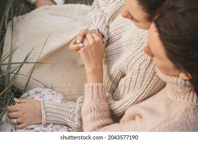 Two Close Girls Hold Hands. Close-up Of The Hands Of Two Girls. Girls In Love Hug And Hold Hands. Women In Sweaters With Large Knitting