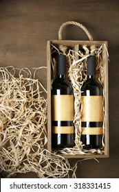 Two Closed Wine Bottles Lying On Straw In Vintage Wooden Box On Wood Background. Top View Point.