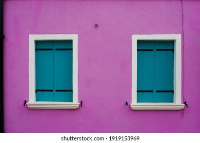 
Two closed wooden shutters in a purple building. Rough wall structure. Front view.