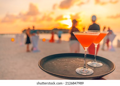 Two Cocktail Drinks With Blur Beach Party People And Colorful Sunset Sky In The Background. Luxury Outdoor Leisure Lifestyle, Relaxing And Romantic Colors, Blurred People Partying On A Summer Evening